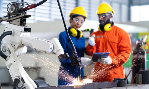 engineer cooperation male and female technician maintenance control relay robot arm system welding with tablet laptop to control quality operate process work heavy industry 4.0 manufacturing factory